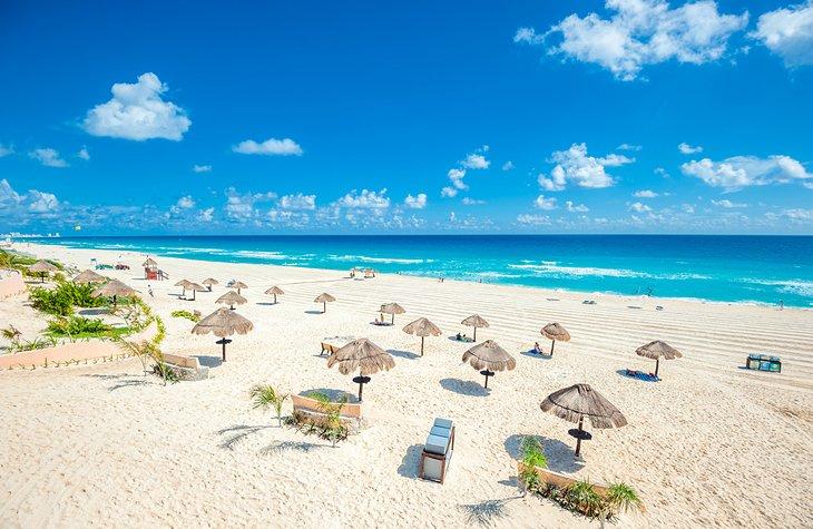 Palapas esparcidas por una playa de arena blanca en Cancún