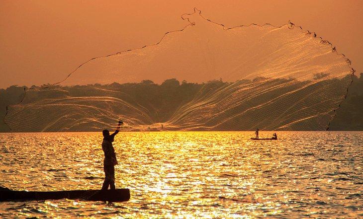 Pêcheur lançant son filet au coucher du soleil sur le lac Victoria
