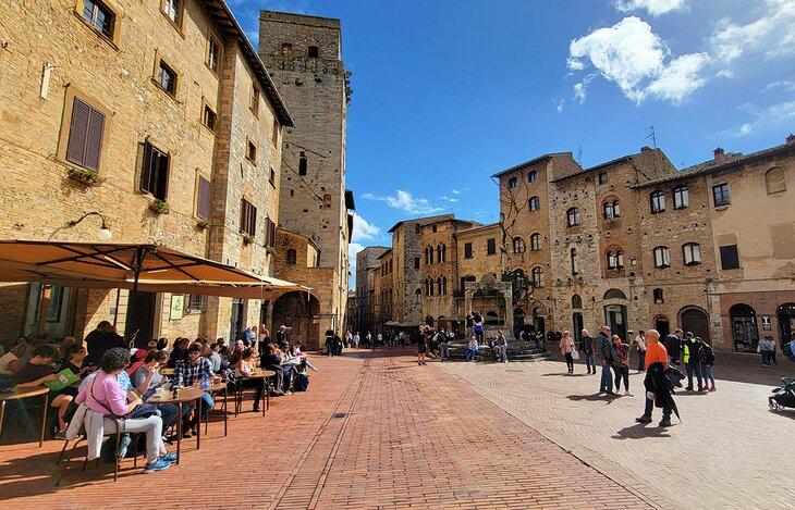 Mesas y paraguas en la Piazza della Cisterna en San Gimignano
