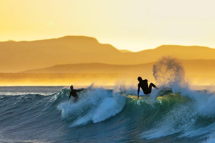 Des surfeurs profitant des Supertubes au lever du soleil