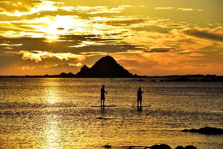 Paddleboarders à Princess Bay au coucher du soleil