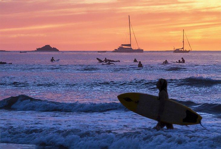 Surfistas silueteados al atardecer en la Playa Tamarindo