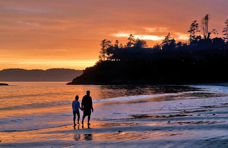 Couple marchant sur la plage au coucher du soleil à Tofino, C.-B.