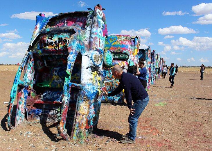 Autor Michael Law pintando en coches en Cadillac Ranch