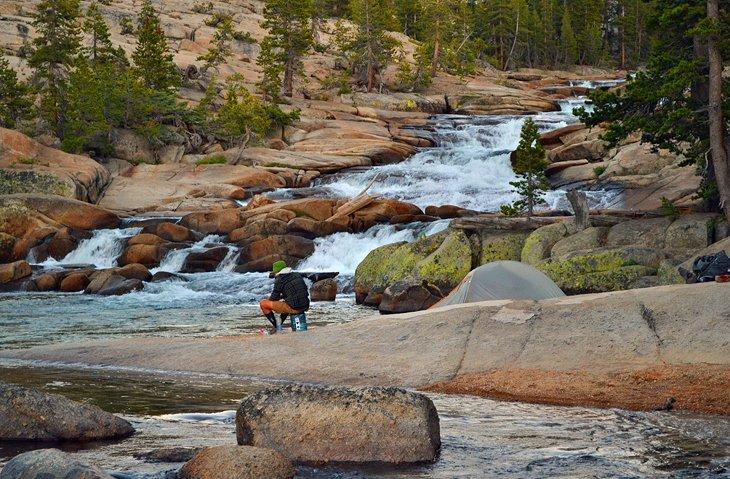 Un excursionista hace la cena a orillas de Tuolumne Falls