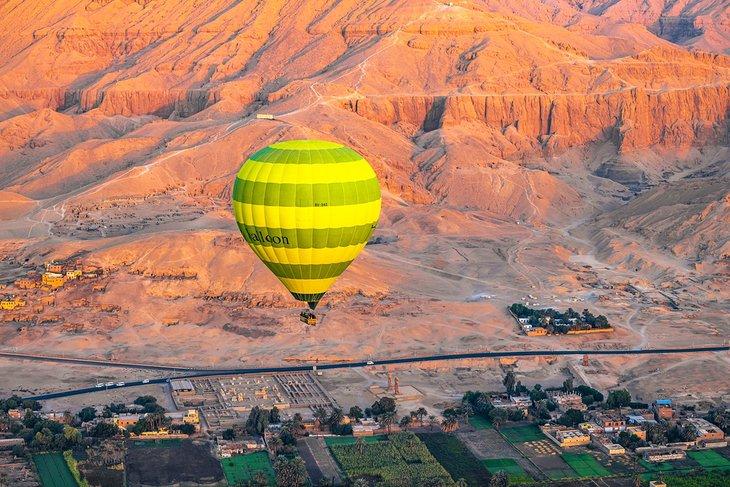 Globo de aire caliente sobre el Valle de los Reyes al amanecer en Luxor, Egipto