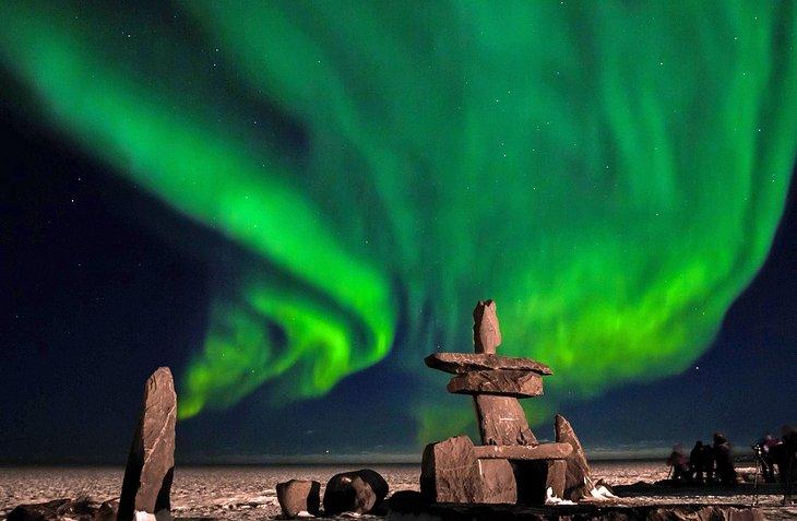 Estructura inuits de piedra con las luces del norte arriba en Churchill, Canadá