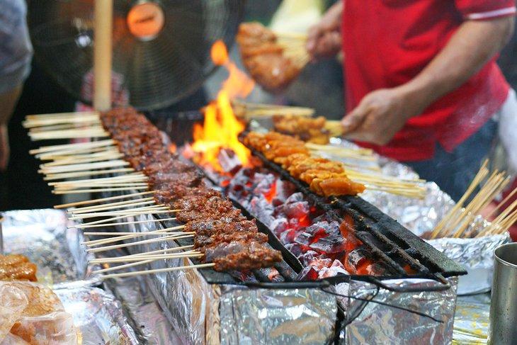 Brochetas de pollo en el mercado de comida callejera Satay en Singapur