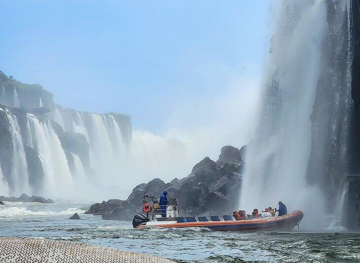 Invitados empapándose debajo de las cataratas en el recorrido en barco mojado de las Cataratas del Iguaçu