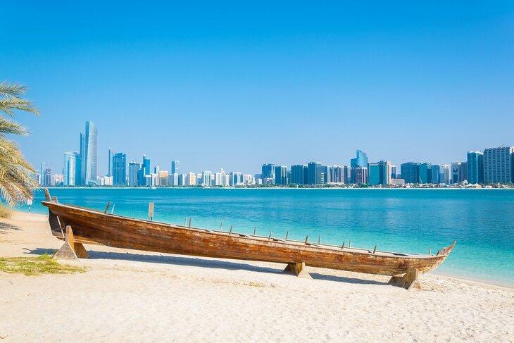 Barco de madera en el Heritage Village, frente al horizonte de Abu Dhabi, Emiratos Árabes Unidos