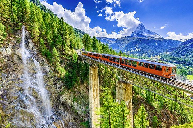 Tren cruzando un puente en Suiza con el Matterhorn a lo lejos